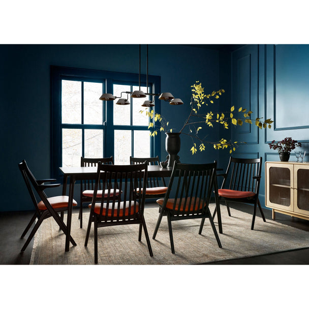 Modern dining room with black spindle-back chairs, deep blue paneled walls, and natural light curated statement furniture from Room to Bloom Inc.